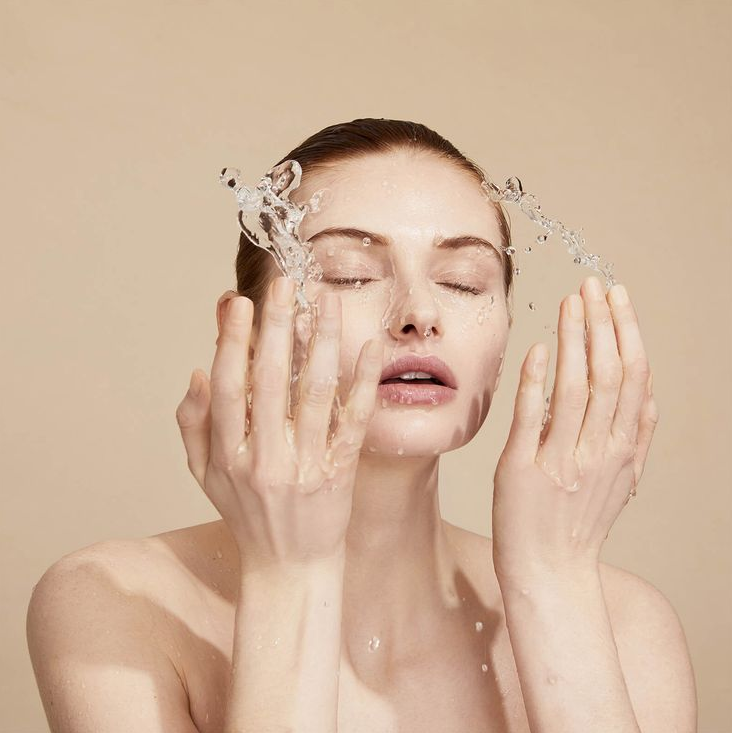 notre histoire femme qui se nettoie le visage à l'eau